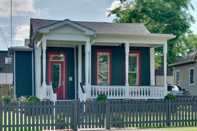 view of front facade featuring a porch, a fenced front yard, and roof with shingles