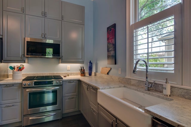 kitchen with a sink, light countertops, gray cabinets, and stainless steel appliances