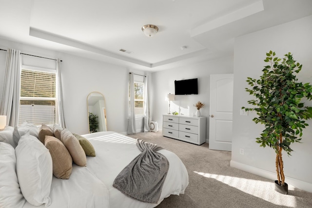 bedroom with a tray ceiling, baseboards, visible vents, and carpet flooring