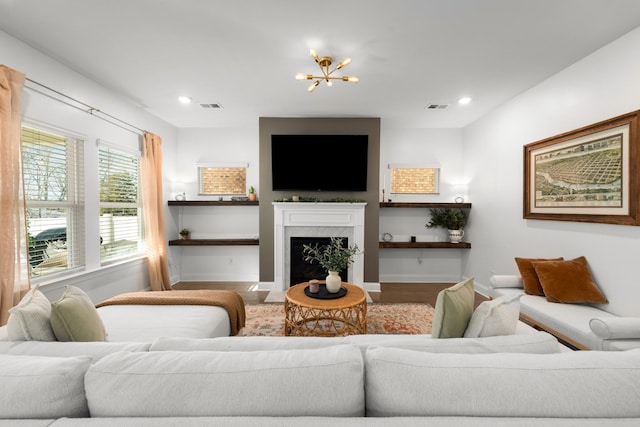 living room featuring visible vents, baseboards, recessed lighting, a high end fireplace, and a chandelier