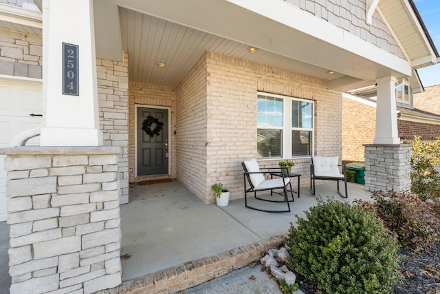 view of exterior entry featuring brick siding and a porch