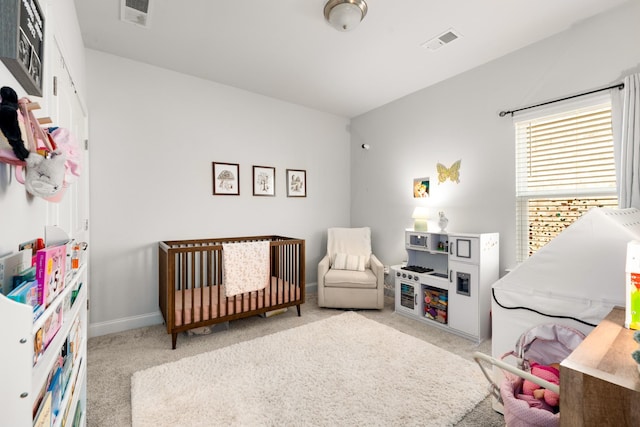 carpeted bedroom with visible vents, baseboards, and a nursery area