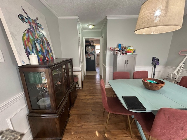 dining area with a wainscoted wall, a textured ceiling, wood finished floors, and ornamental molding