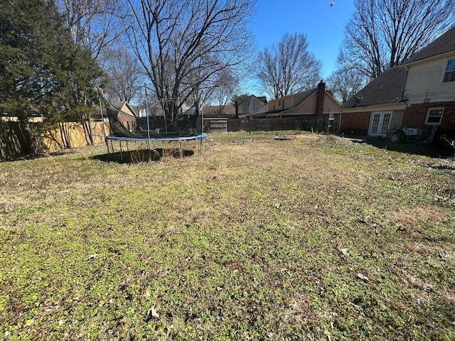 view of yard with a fenced backyard, french doors, and a trampoline