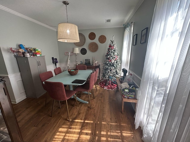 dining space featuring visible vents, ornamental molding, plenty of natural light, and wood finished floors