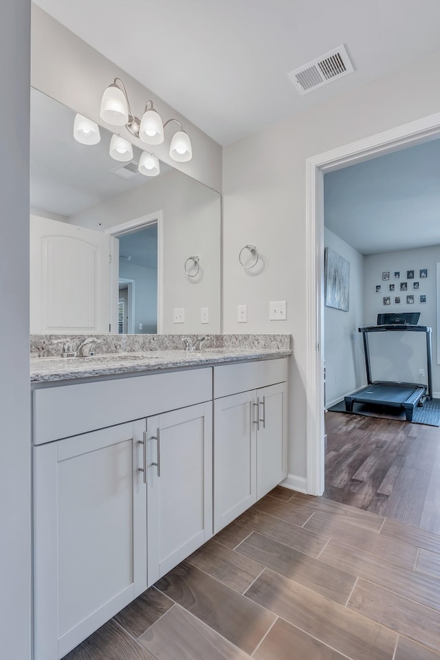 bathroom featuring visible vents, a sink, wood finish floors, and double vanity