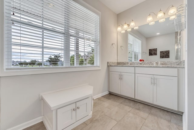 bathroom with double vanity, baseboards, plenty of natural light, and a sink