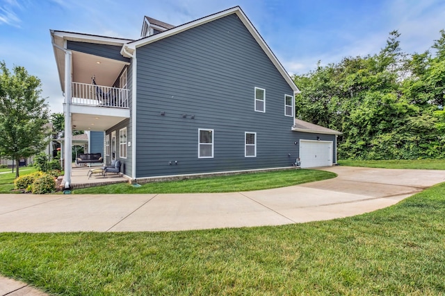 view of side of property featuring a patio, a balcony, driveway, a garage, and a lawn