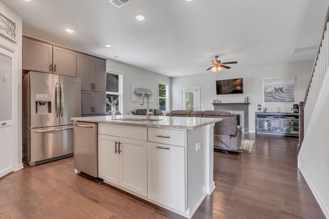 kitchen with a sink, stainless steel appliances, a fireplace, and dark wood-style flooring