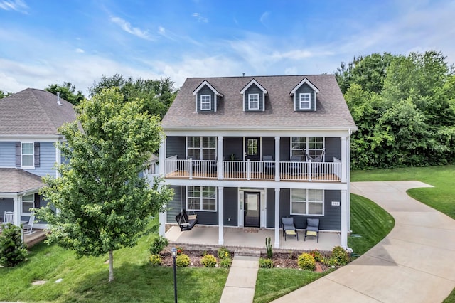 view of front of home with a front yard, a balcony, a patio area, and a shingled roof