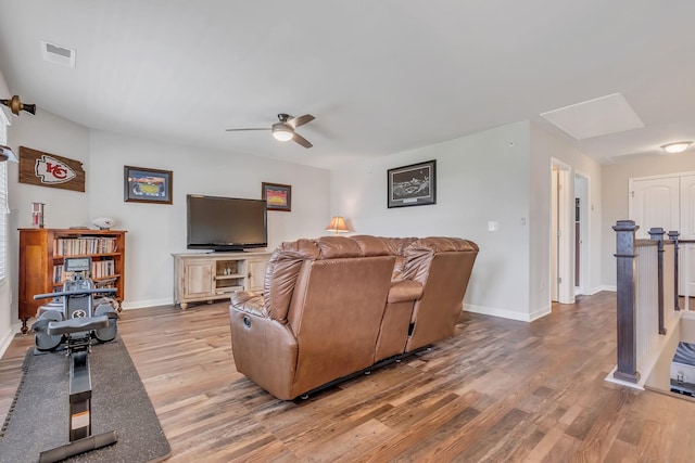 living room featuring a ceiling fan, light wood-style floors, visible vents, and baseboards