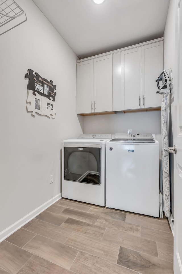 clothes washing area with cabinet space, independent washer and dryer, baseboards, and wood tiled floor