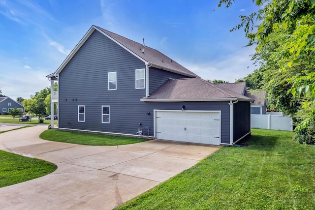 view of property exterior with fence, driveway, roof with shingles, an attached garage, and a yard