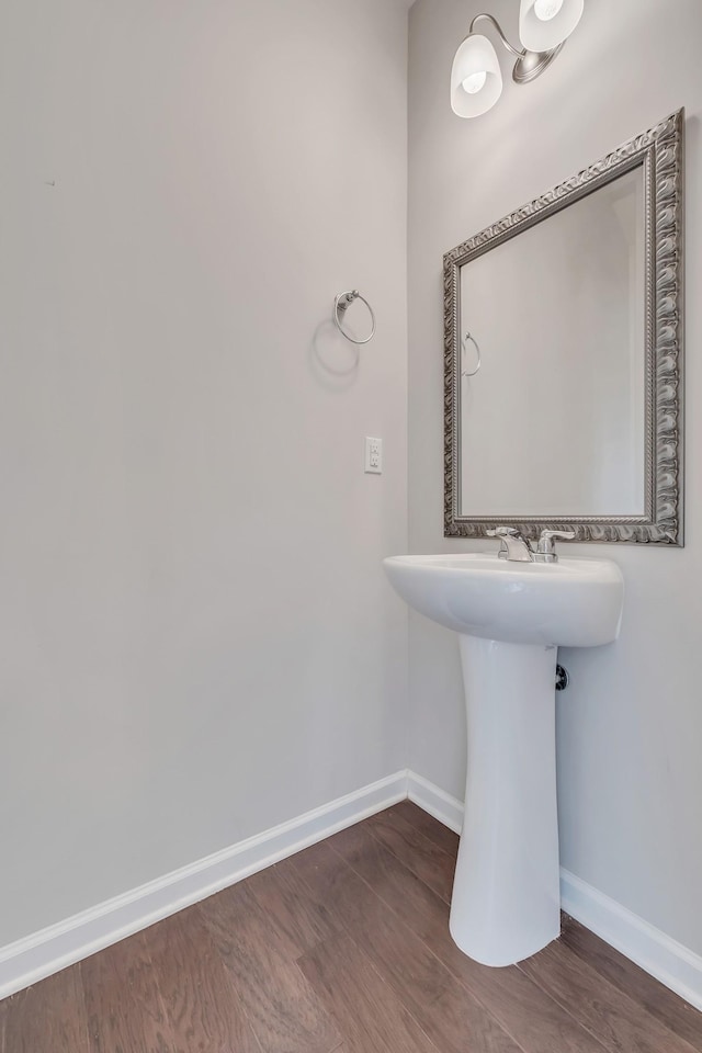 bathroom featuring wood finished floors, baseboards, and a sink