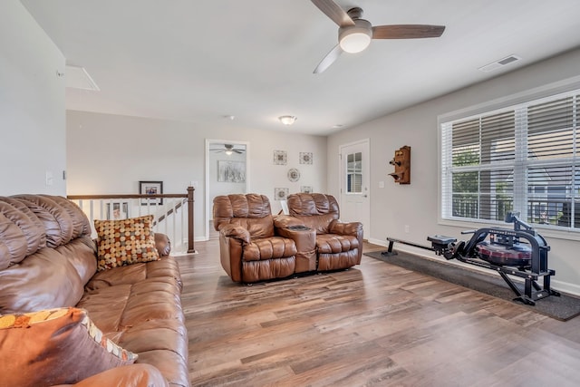 living area featuring a ceiling fan, wood finished floors, visible vents, and baseboards