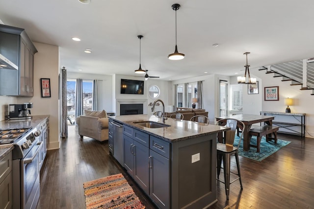 kitchen featuring a breakfast bar, a sink, open floor plan, appliances with stainless steel finishes, and a fireplace