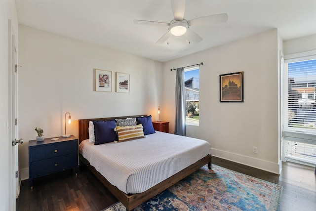 bedroom with dark wood finished floors, a ceiling fan, and baseboards