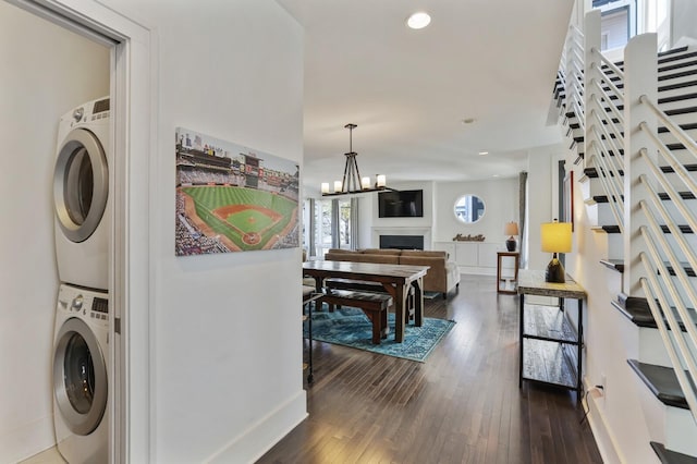 washroom featuring laundry area, recessed lighting, stacked washer and clothes dryer, a fireplace, and dark wood-style floors