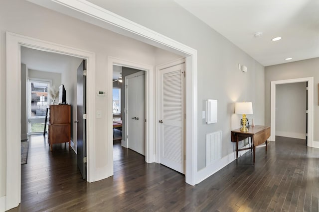 hallway featuring recessed lighting, visible vents, baseboards, and dark wood-style floors