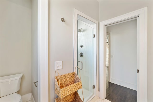 full bath featuring toilet, wood finished floors, a stall shower, and baseboards