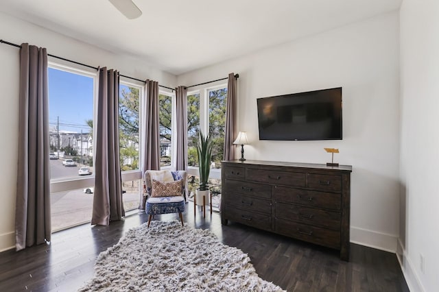 living area featuring baseboards, ceiling fan, and dark wood-style flooring