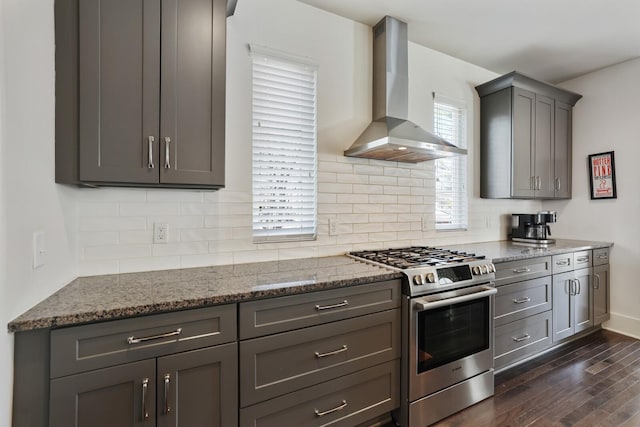 kitchen featuring backsplash, gray cabinetry, dark wood-style floors, stainless steel gas range, and wall chimney exhaust hood