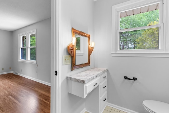 bathroom with toilet, vanity, baseboards, and wood finished floors