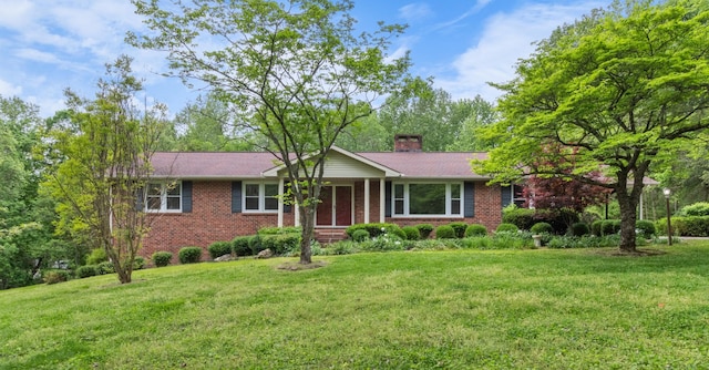 ranch-style house with brick siding, a chimney, and a front lawn