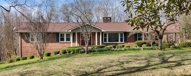 ranch-style house with brick siding, a chimney, and a front yard