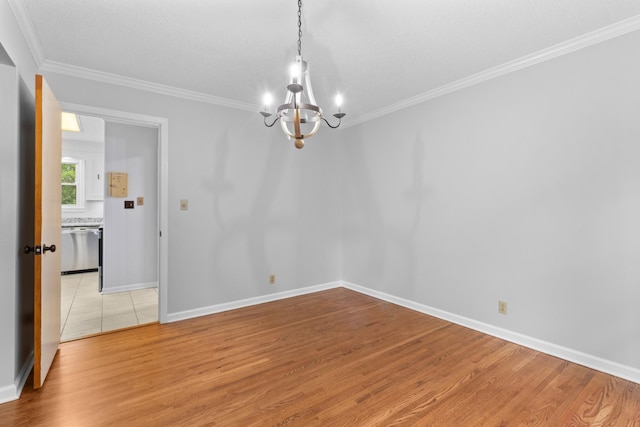 spare room with light wood-type flooring, an inviting chandelier, and crown molding