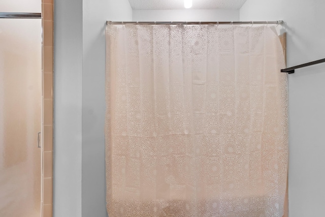 details with curtained shower and a textured ceiling