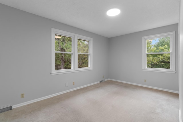 empty room with visible vents, light colored carpet, and baseboards