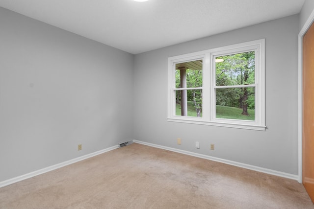 spare room with visible vents, light colored carpet, and baseboards