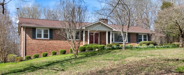 ranch-style home with brick siding, a chimney, and a front yard