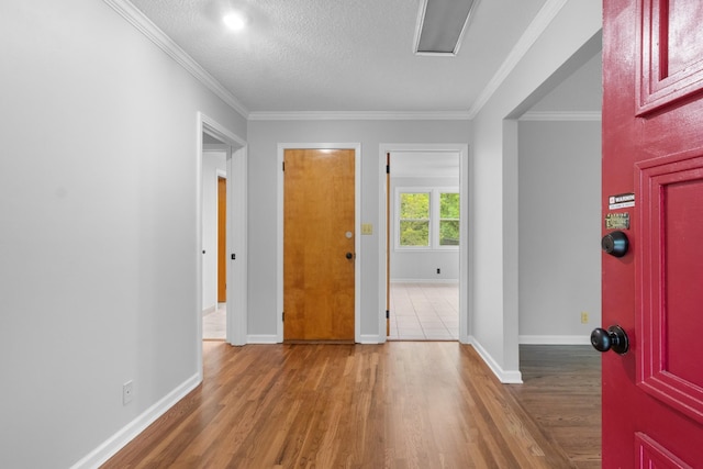 entrance foyer featuring ornamental molding, a textured ceiling, baseboards, and wood finished floors