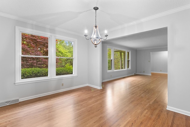 spare room featuring baseboards, visible vents, light wood-style flooring, crown molding, and a notable chandelier