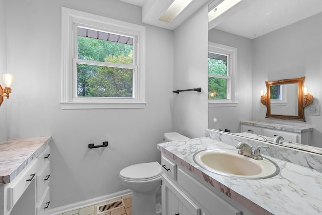 half bath with a wealth of natural light, visible vents, baseboards, and toilet