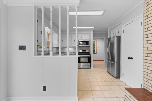 kitchen with ornamental molding, a peninsula, appliances with stainless steel finishes, white cabinets, and light tile patterned floors