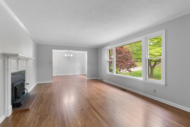 unfurnished living room featuring a notable chandelier, wood finished floors, and a textured ceiling