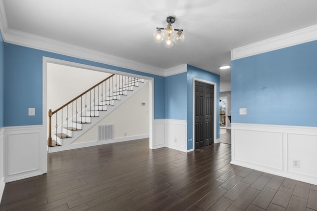 unfurnished living room with visible vents, a wainscoted wall, stairs, an inviting chandelier, and dark wood-style flooring