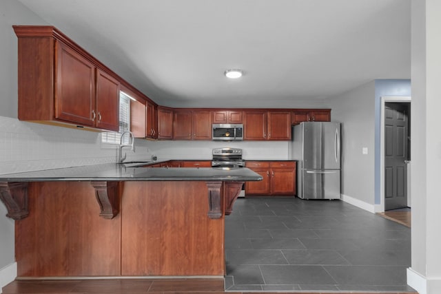 kitchen featuring a sink, dark countertops, stainless steel appliances, a peninsula, and baseboards