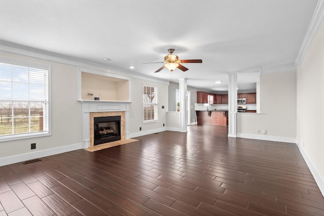 unfurnished living room featuring a ceiling fan, visible vents, dark wood finished floors, a tile fireplace, and ornamental molding