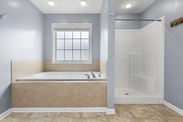 bathroom featuring a shower, baseboards, and a garden tub