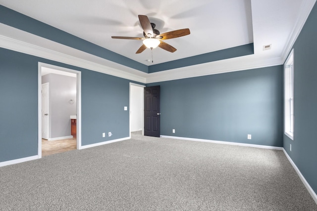 carpeted empty room featuring baseboards, a raised ceiling, ceiling fan, and crown molding