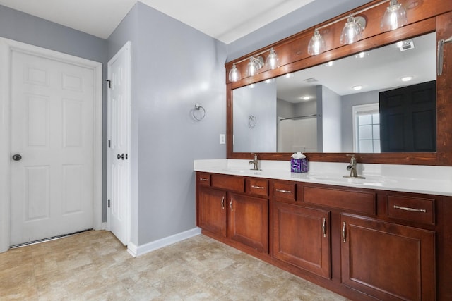 bathroom with a sink, an enclosed shower, baseboards, and double vanity