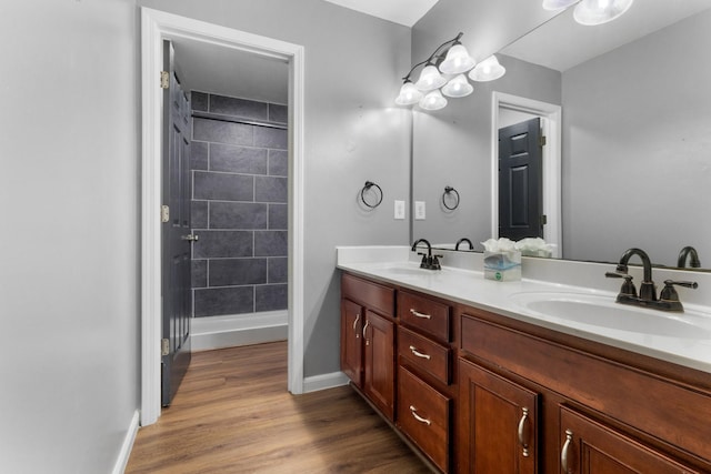 bathroom with a sink, baseboards, wood finished floors, and double vanity