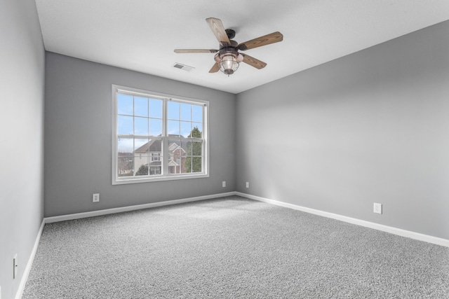 carpeted spare room with visible vents, ceiling fan, and baseboards