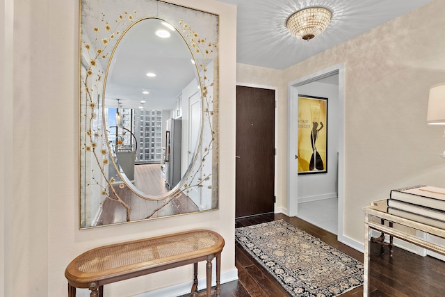 foyer entrance with arched walkways, baseboards, and wood finished floors