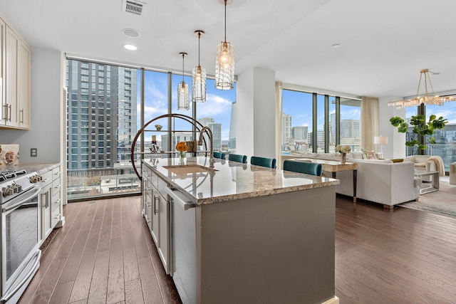 kitchen with visible vents, a city view, expansive windows, stainless steel appliances, and dark wood-style flooring