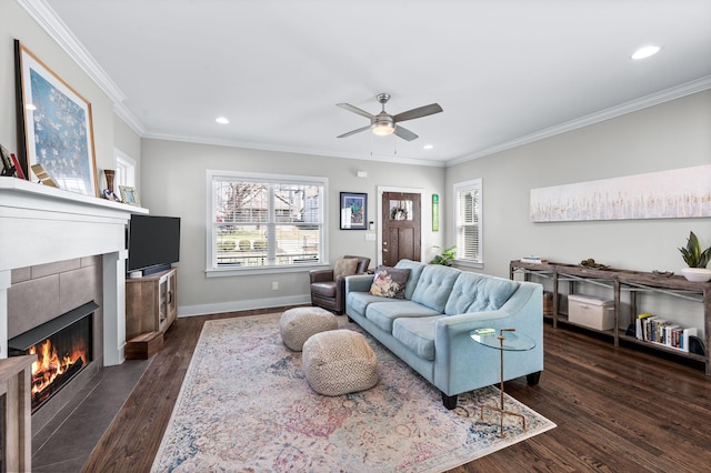 living room with baseboards, ornamental molding, recessed lighting, a tile fireplace, and dark wood-style flooring